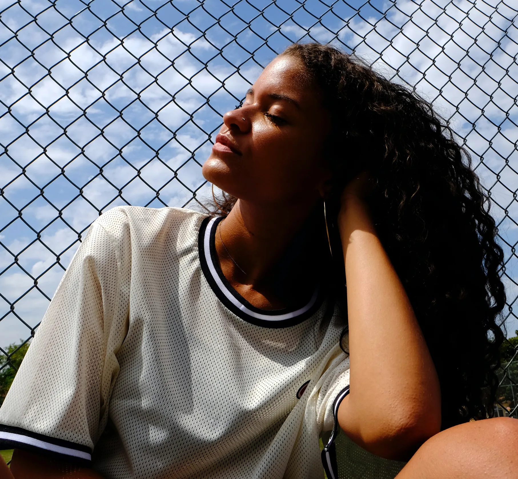 Young woman relaxing outdoors with eyes closed, face tilted towards the sun
